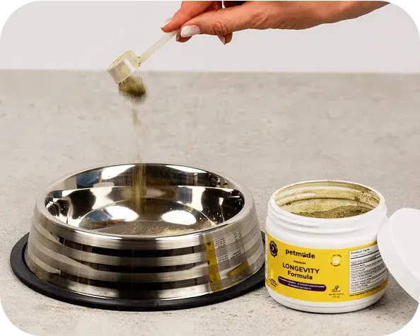 Pouring PetMade Longevity Formula powder into a bowl food bowl