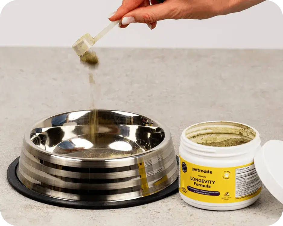 Pouring PetMade Longevity Formula powder into a dog food bowl