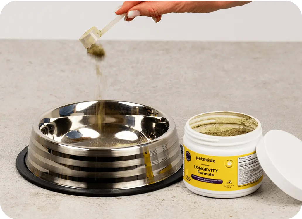 Pouring PetMade Longevity Formula powder into a bowl food bowl